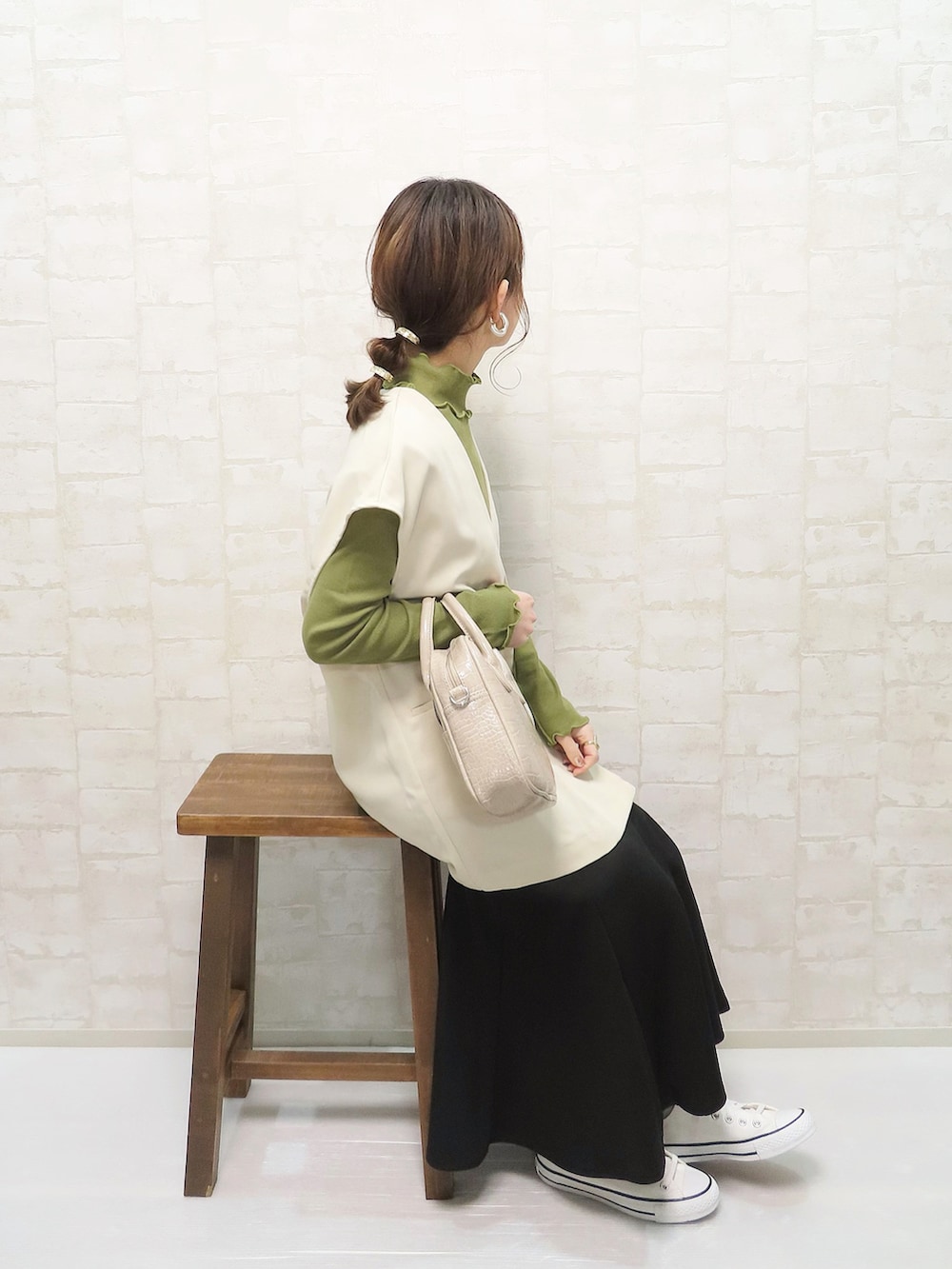 ホワイト系のベスト、グリーン系のTシャツ/カットソー、ブラック系のスカートを着用したレディースの春コーディネートの2枚目の写真