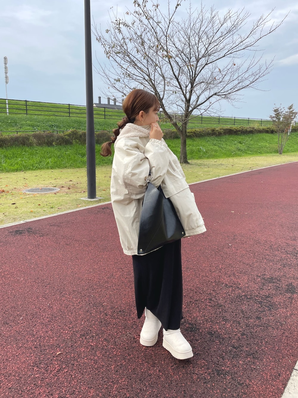 ホワイト系のブルゾン、ブラック系のバッグ、ベージュ系のブーツを着用したレディースの冬コーディネートの3枚目の写真