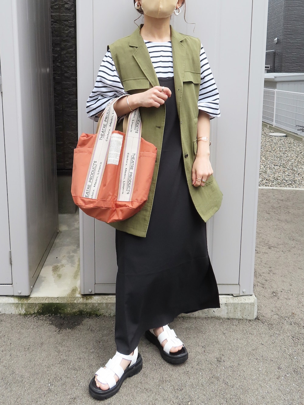 ブラック系のTシャツ/カットソー、グリーン系のベスト、オレンジ系のトートバッグを着用したレディースの夏コーディネートの2枚目の写真