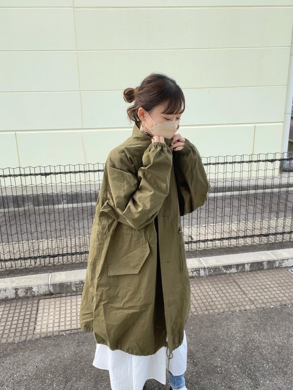 グリーン系のモッズコート、ホワイト系のシャツワンピース、ブラック系のボストンバッグを着用したレディースの秋コーディネートの4枚目の写真