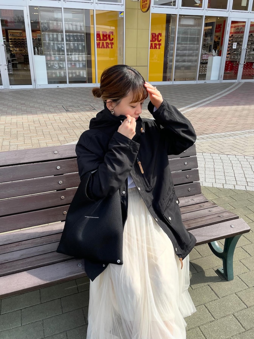 ブラック系のマウンテンパーカー、ホワイト系のTシャツ/カットソー、ホワイト系のスカートを着用したレディースの春コーディネートの4枚目の写真