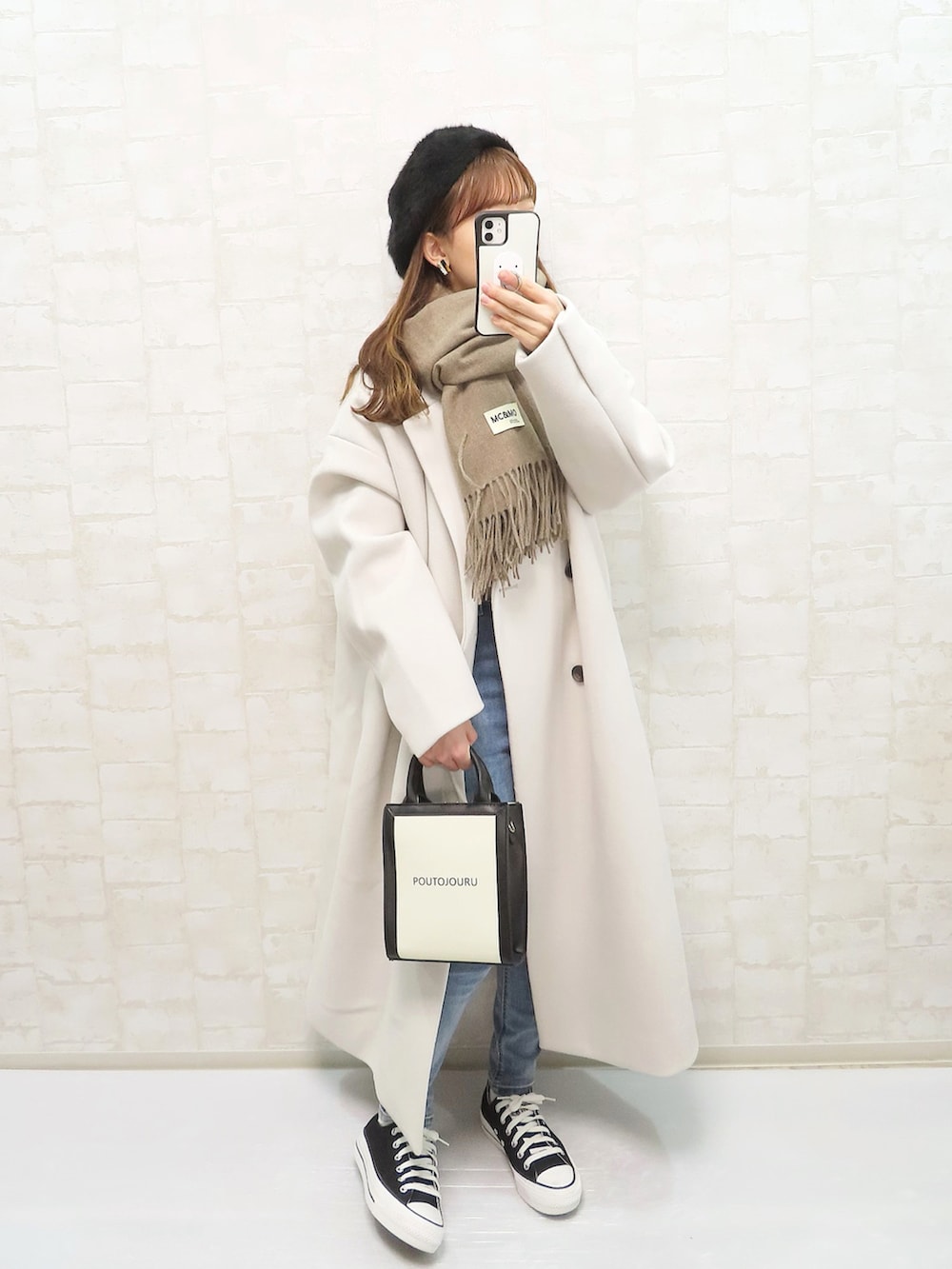 グレー系のチェスターコート、ベージュ系のニット/セーター、ブルー系のデニムパンツを着用したレディースの冬コーディネートの2枚目の写真