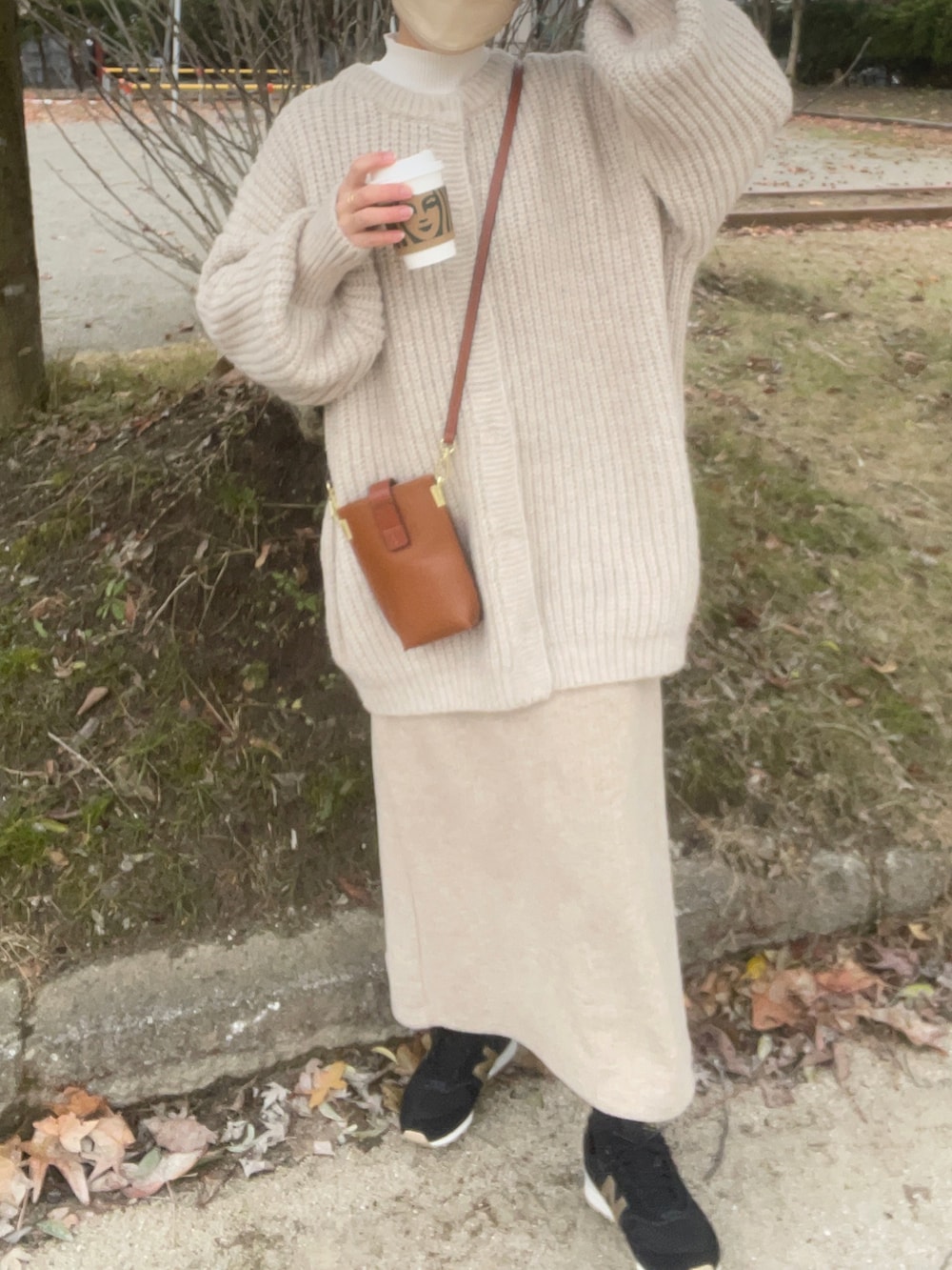 ホワイト系のカーディガン/ボレロ、ホワイト系のニット/セーター、ベージュ系のスカートを着用したレディースの冬コーディネートの3枚目の写真