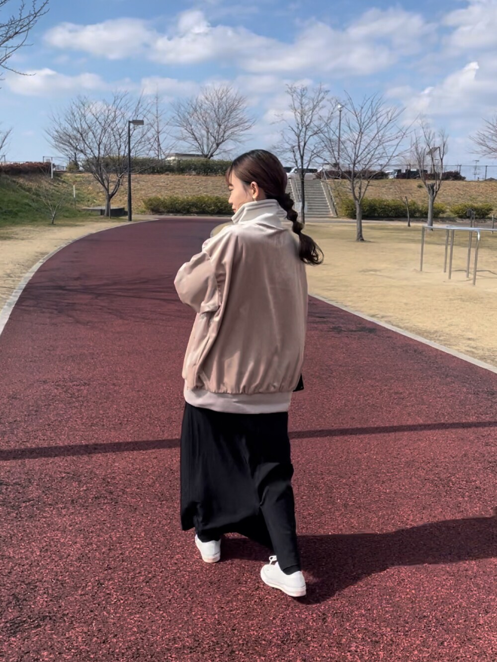 ベージュ系のスウェット、ブラック系のワンピース、ホワイト系のスニーカーを着用したレディースの春コーディネートの3枚目の写真