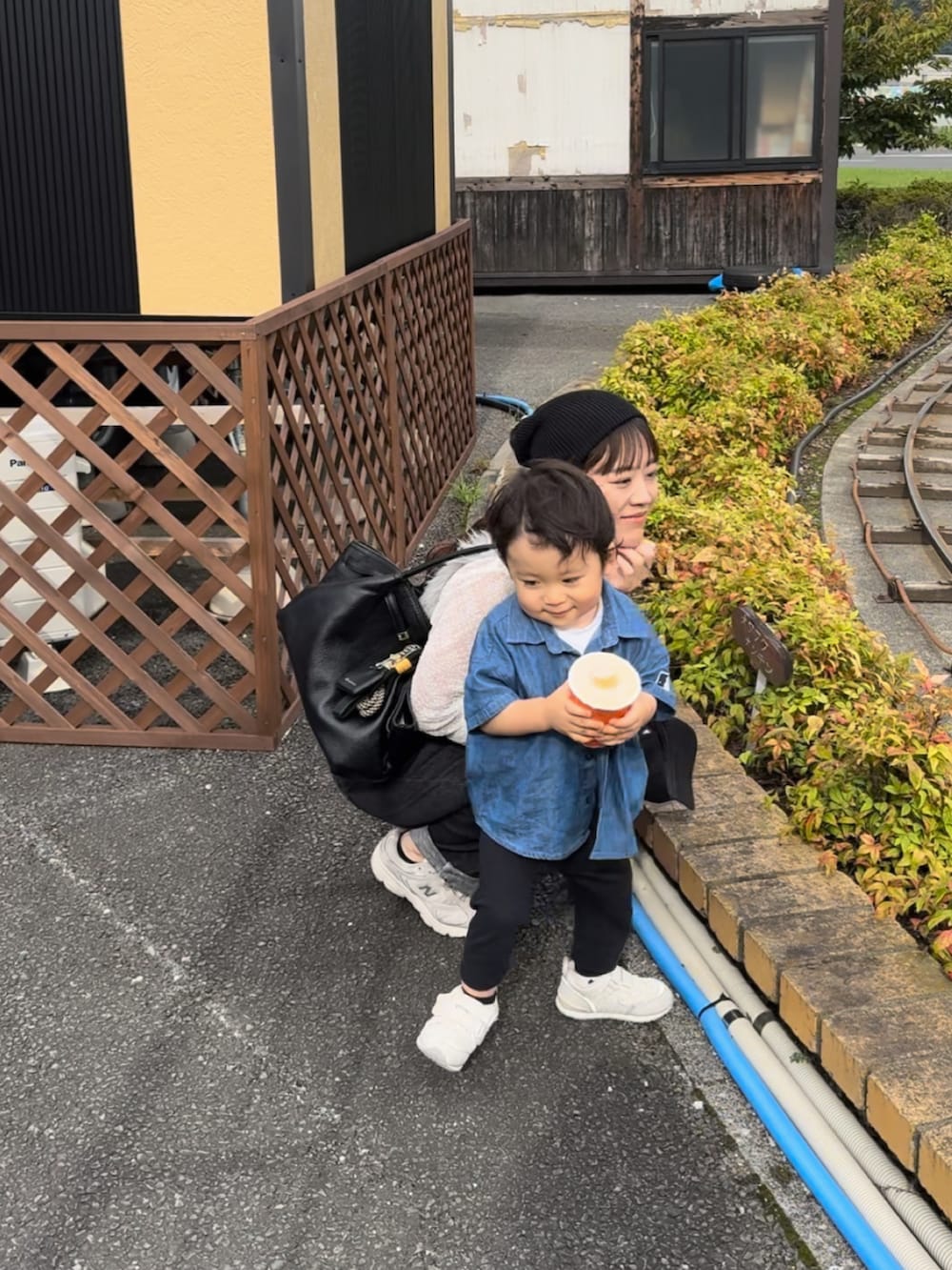 ホワイト系のスニーカー、グレー系のベスト、ブラック系のパンツを着用したレディースの秋コーディネートの3枚目の写真