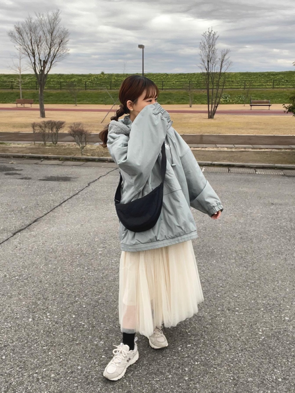 ブルー系のブルゾン、ホワイト系のスカート、ブラック系のショルダーバッグを着用したレディースの冬コーディネートの2枚目の写真