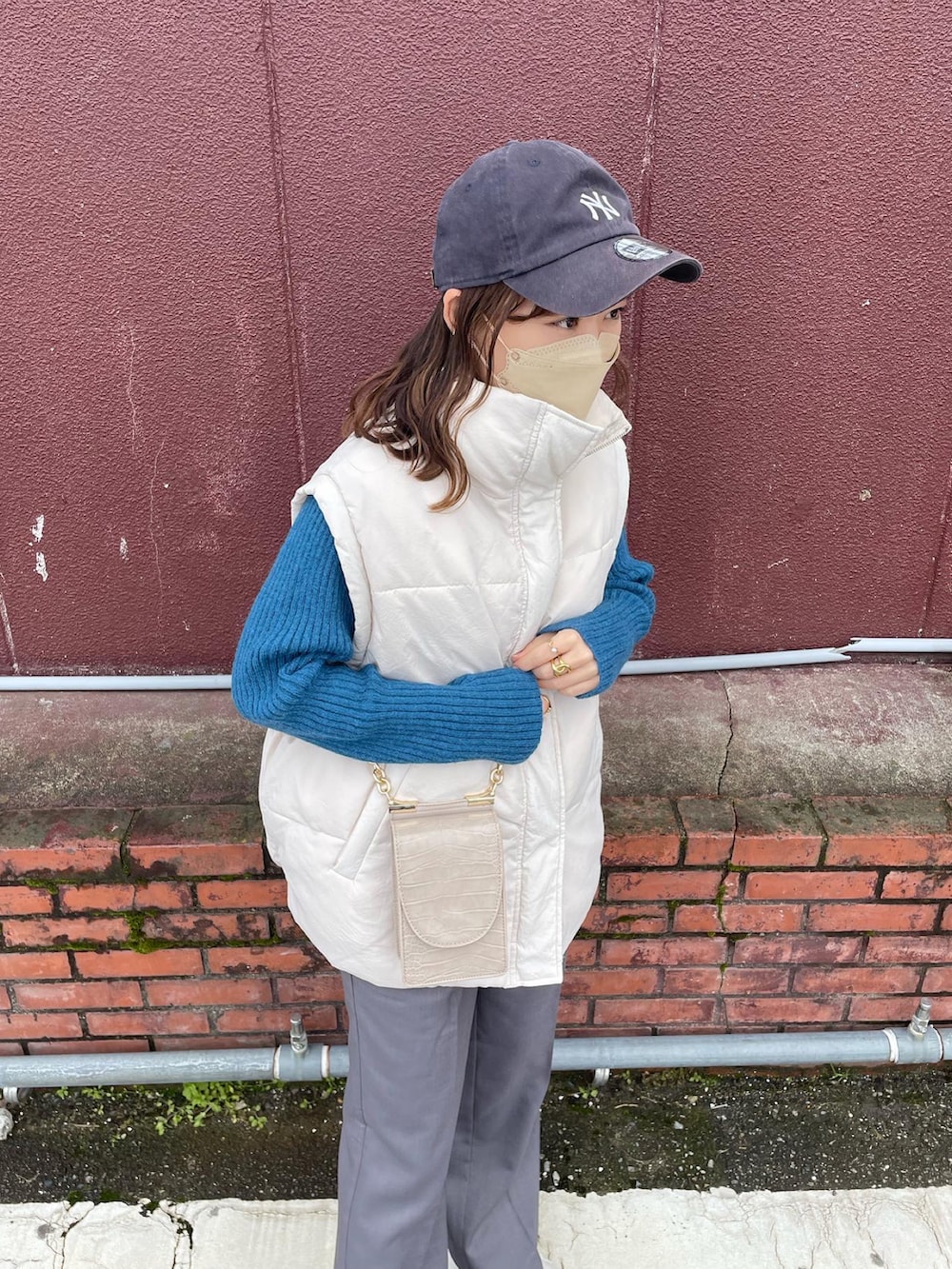 グレー系のパンツ、ブルー系のニット/セーター、ホワイト系のダウンベストを着用したレディースの冬コーディネートの2枚目の写真