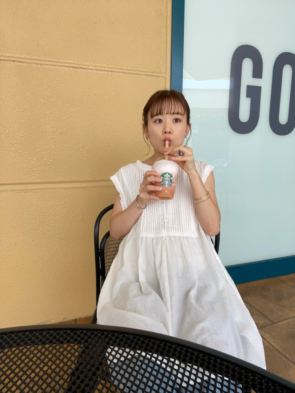 ホワイト系のトップス、ブルー系のデニムパンツ、ブラック系のハンドバッグを着用したレディースの夏コーディネートの3枚目の写真