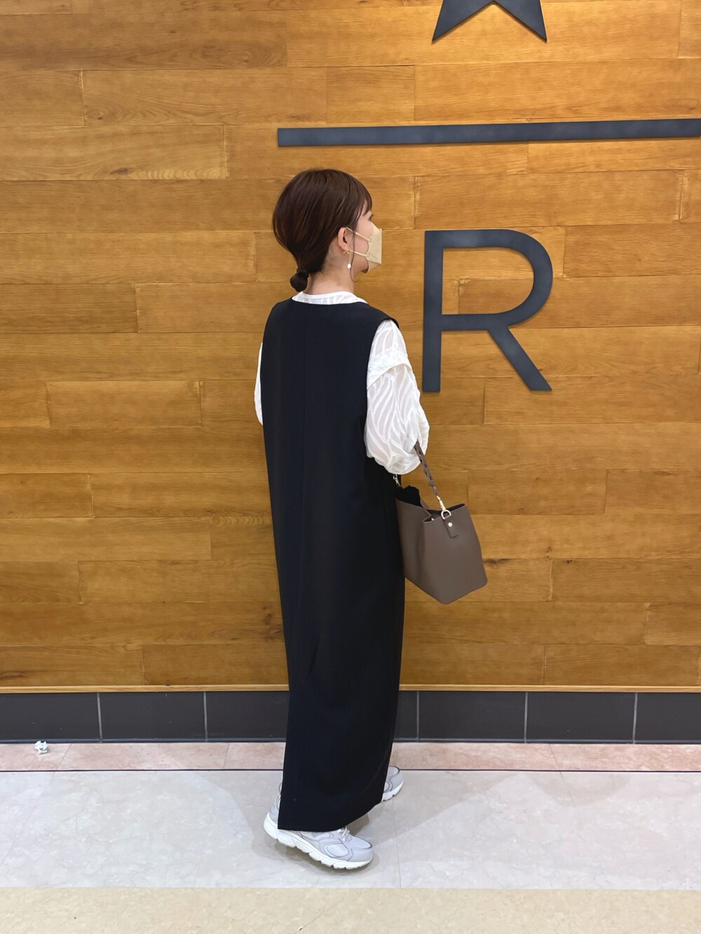 ブラック系のジャンパースカート、ホワイト系のシャツ/ブラウス、ブラウン系のバッグを着用したレディースの春コーディネートの4枚目の写真