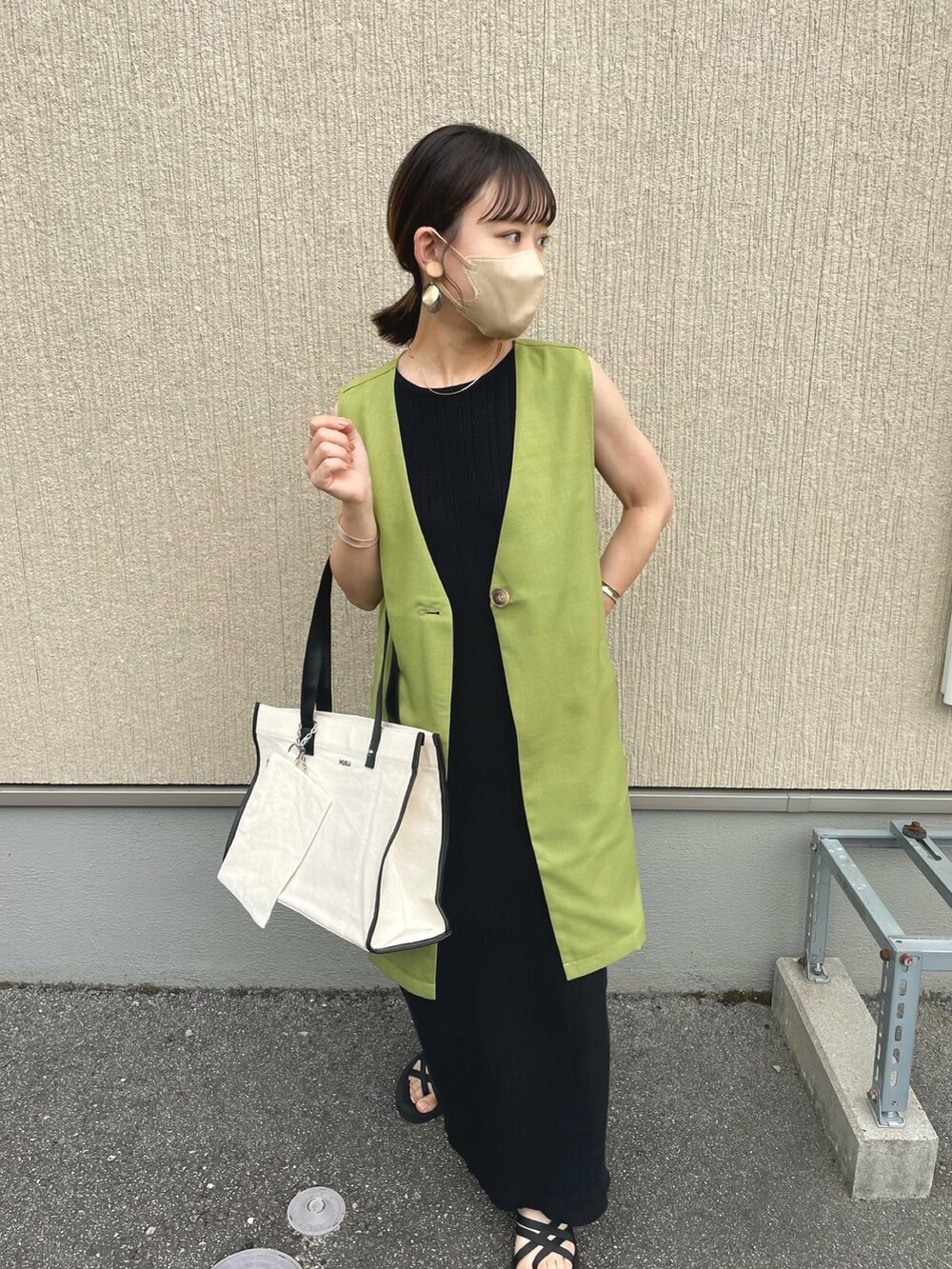 ホワイト系のトートバッグ、グリーン系のベスト、ブラック系のワンピースを着用したレディースの夏コーディネートの2枚目の写真