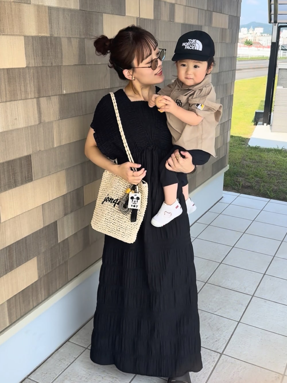 ブラック系のワンピース、ベージュ系のかごバッグ、ブラック系のサンダルを着用したレディースの夏コーディネートの3枚目の写真