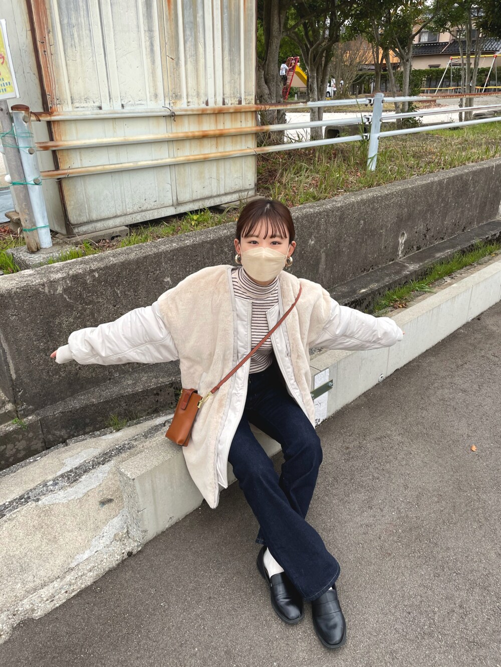 ベージュ系のブルゾン、ホワイト系のニット/セーター、ブルー系のデニムパンツを着用したレディースの冬コーディネートの2枚目の写真