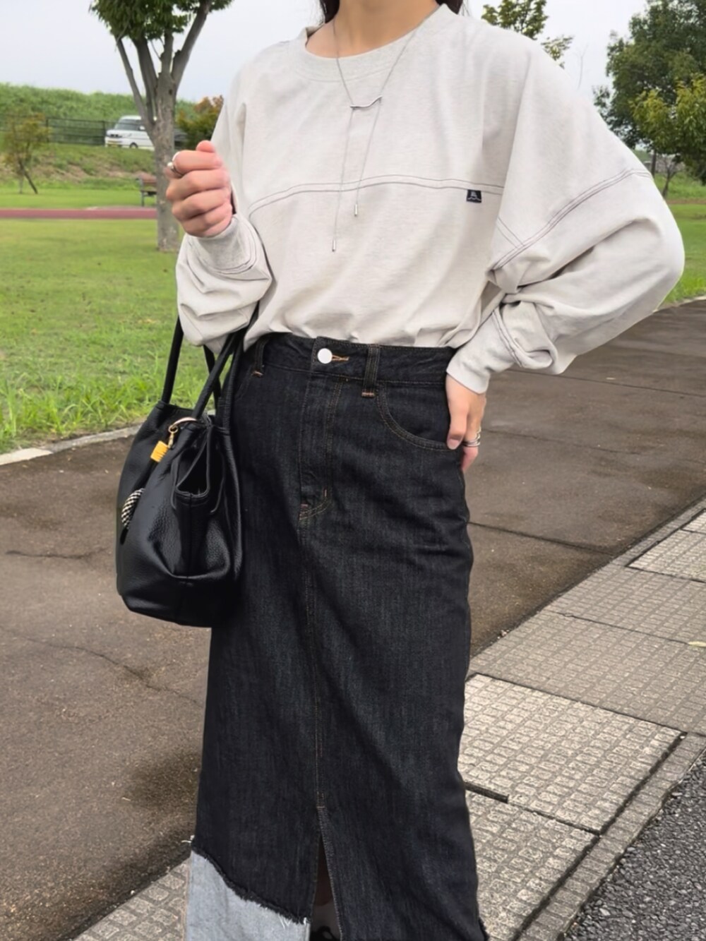 ベージュ系のTシャツ/カットソー、ブラック系のデニムスカート、グレー系のベストを着用したレディースの秋コーディネートの4枚目の写真