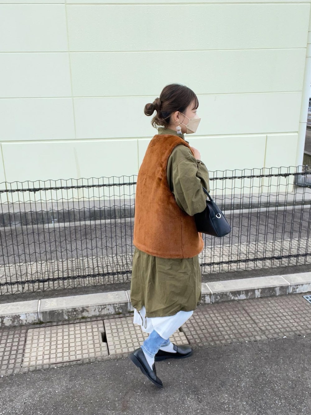 グリーン系のモッズコート、ホワイト系のシャツワンピース、ブラック系のボストンバッグを着用したレディースの秋コーディネートの2枚目の写真