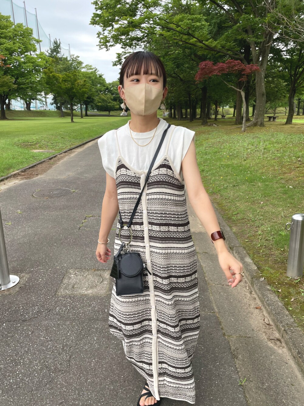 ベージュ系のワンピース、ホワイト系のニット/セーター、ブラック系のショルダーバッグを着用したレディースの夏コーディネートの4枚目の写真