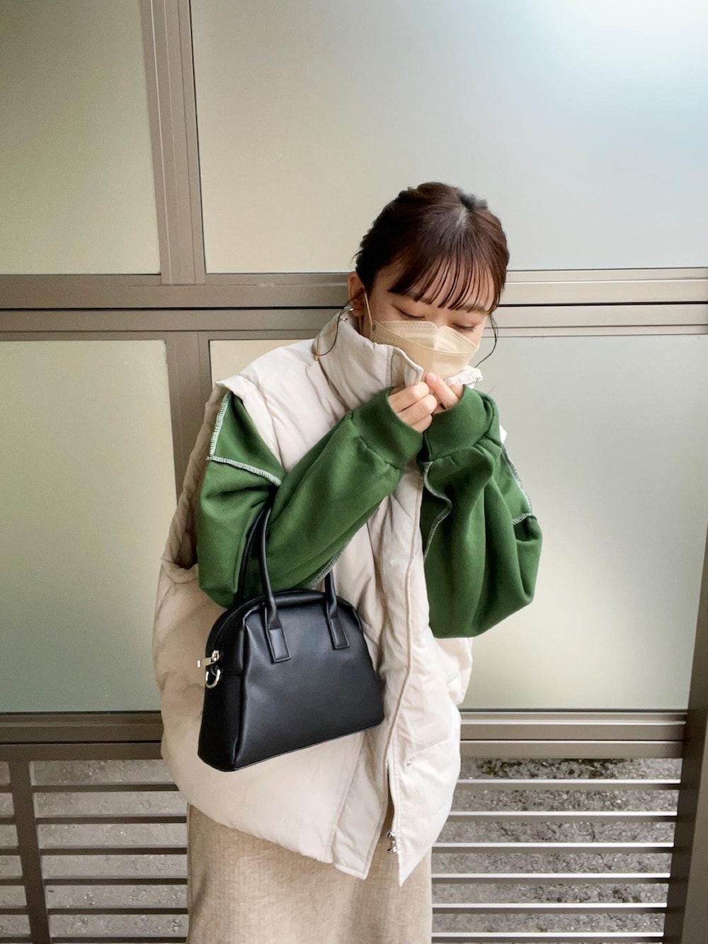 グリーン系のスウェット、ホワイト系のダウンベスト、ブラック系のボストンバッグを着用したレディースの秋コーディネートの2枚目の写真