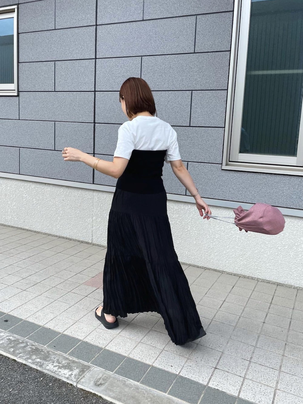 ブラック系のチューブトップ、ブラック系のスカート、ピンク系のショルダーバッグを着用したレディースの夏コーディネートの2枚目の写真