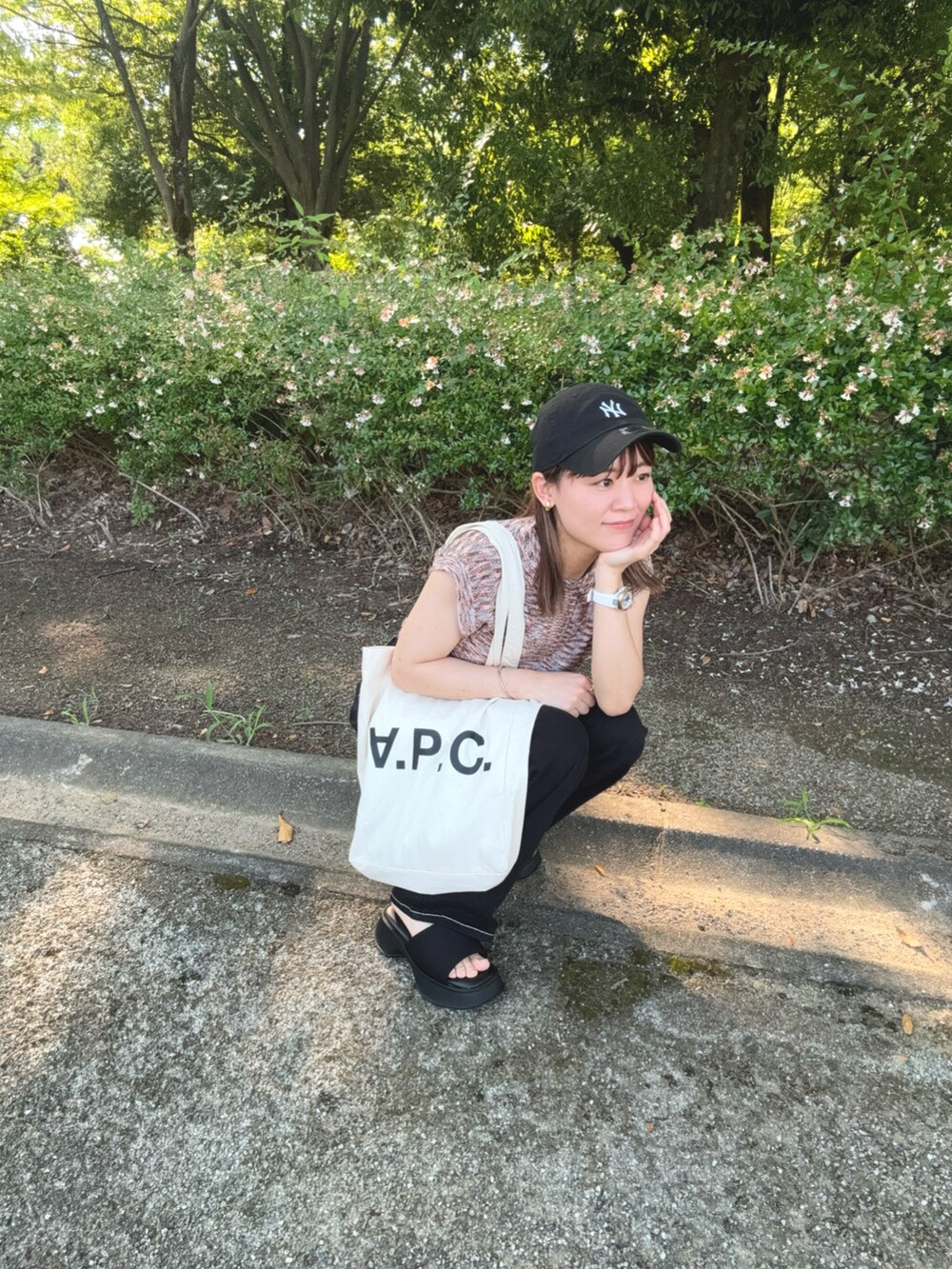 ピンク系のニット/セーター、ブラック系のデニムパンツ、ブラック系のサンダルを着用したレディースの夏コーディネートの5枚目の写真
