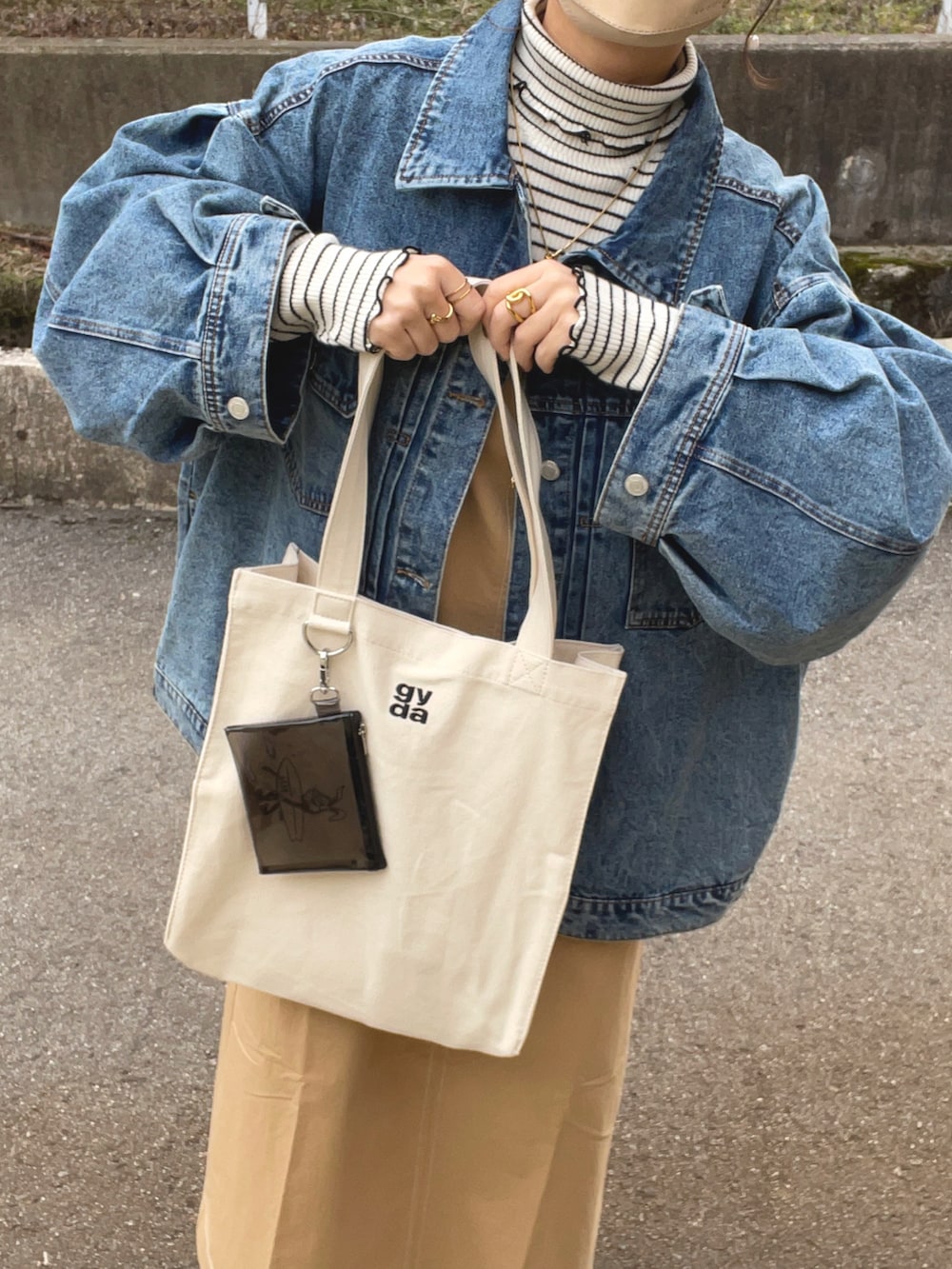 ベージュ系のワンピース、ホワイト系のトートバッグ、ブルー系のデニムジャケットを着用したレディースの春コーディネートの3枚目の写真