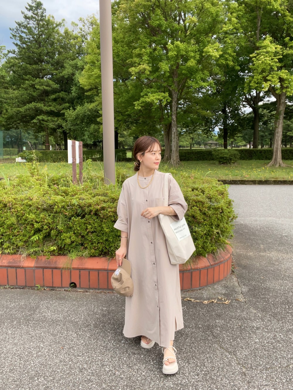 グレー系のシャツワンピース、ホワイト系のトートバッグ、ホワイト系のサンダルを着用したレディースの夏コーディネートの4枚目の写真
