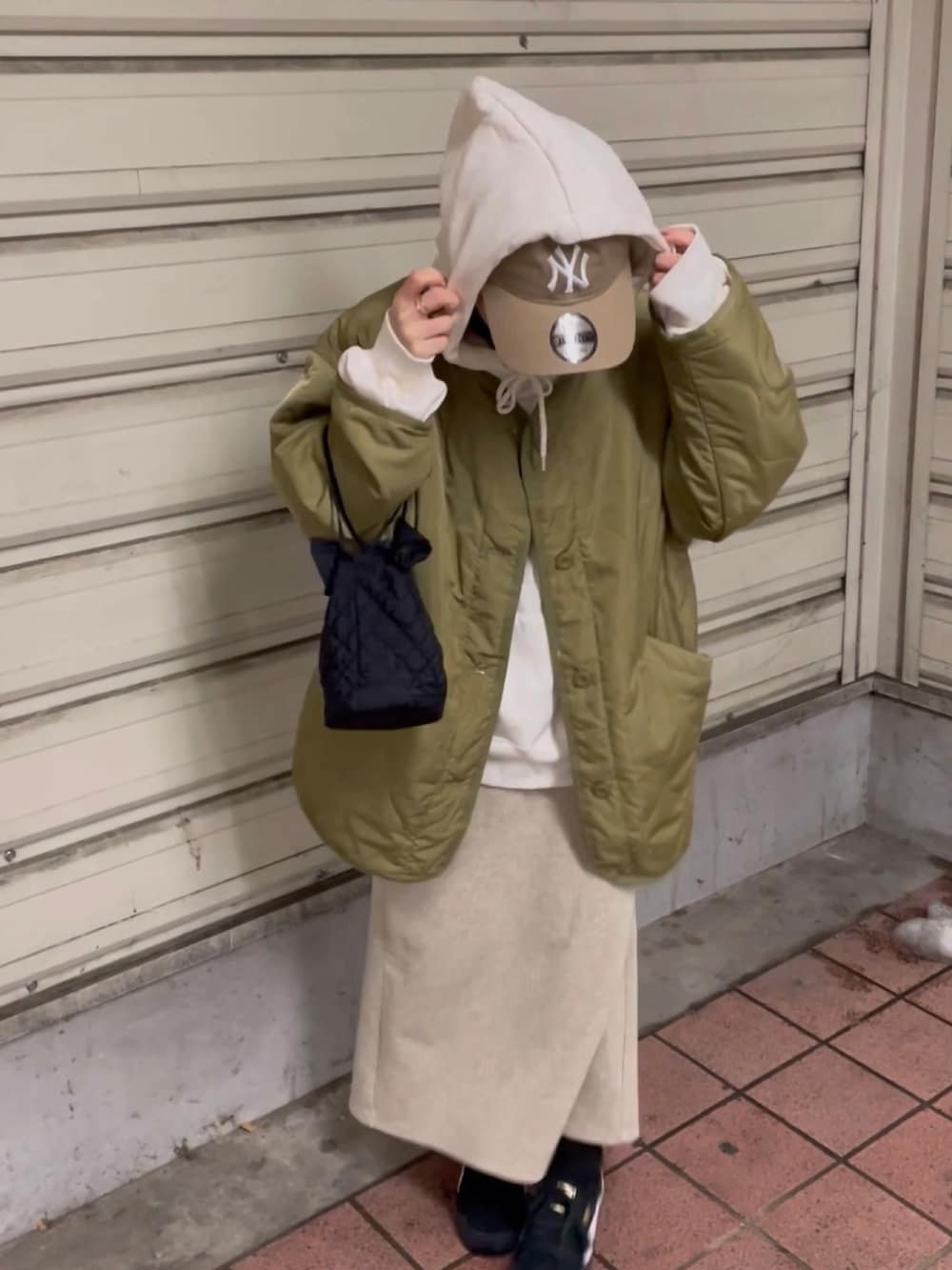 グリーン系のノーカラージャケット、ホワイト系のパーカー、ベージュ系のスカートを着用したレディースの冬コーディネートの2枚目の写真