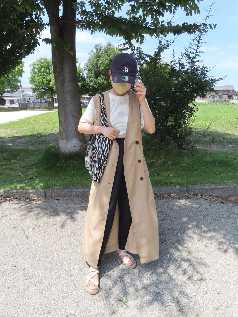 ベージュ系のベスト、ホワイト系のニット/セーター、ブラック系のその他パンツを着用したレディースの夏コーディネートの3枚目の写真