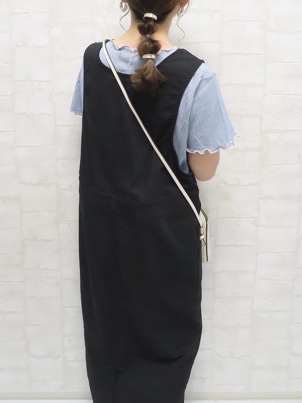 ブルー系のTシャツ/カットソー、ブラック系のジャンパースカート、ベージュ系のサンダルを着用したレディースの夏コーディネートの5枚目の写真