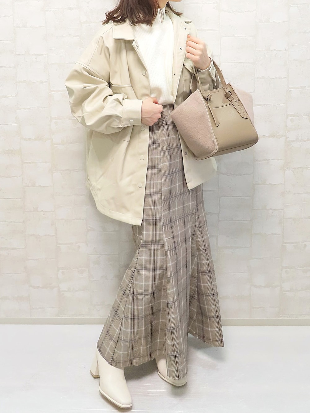 ホワイト系のその他アウター、ホワイト系のニット/セーター、ブラウン系のスカートを着用したレディースの冬コーディネートの2枚目の写真