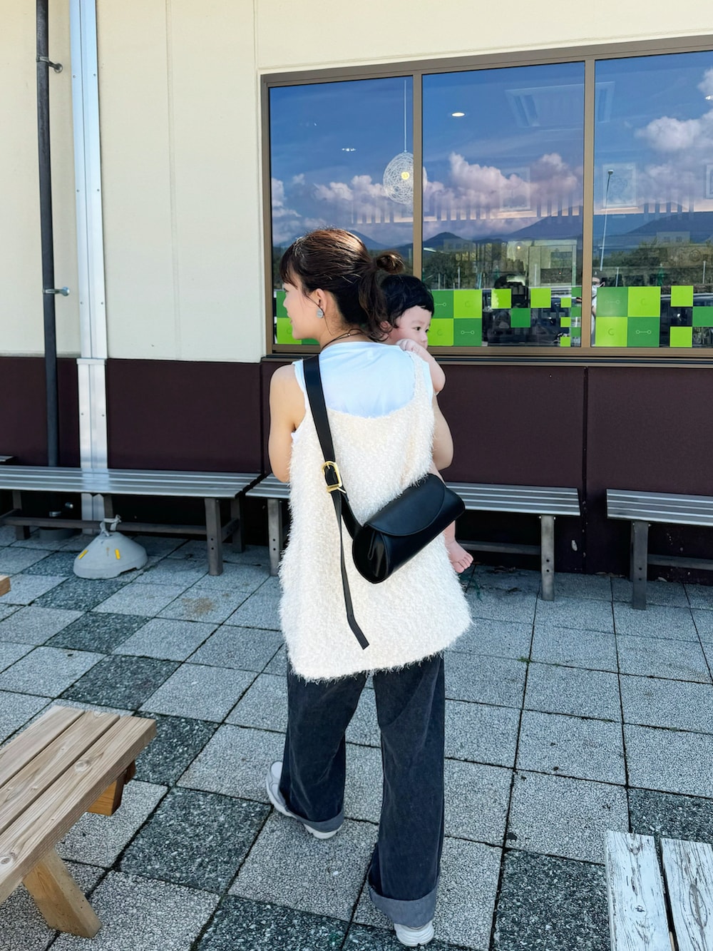 ホワイト系のベスト、ブラック系のショルダーバッグ、ブラック系のデニムパンツを着用したレディースの秋コーディネートの5枚目の写真