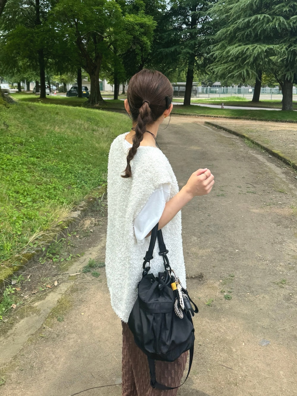 ブラウン系のスカート、ホワイト系のトップス、ブラック系のバッグを着用したレディースの夏コーディネートの3枚目の写真