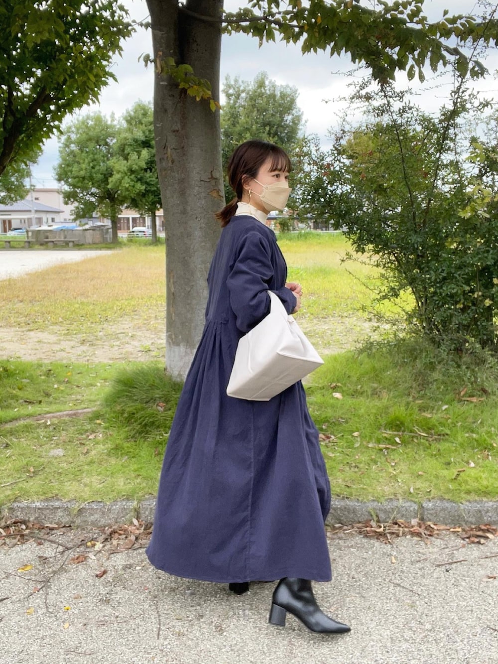 ブルー系のワンピース、ブラック系のブーツ、ホワイト系のニット/セーターを着用したレディースの秋コーディネートの2枚目の写真