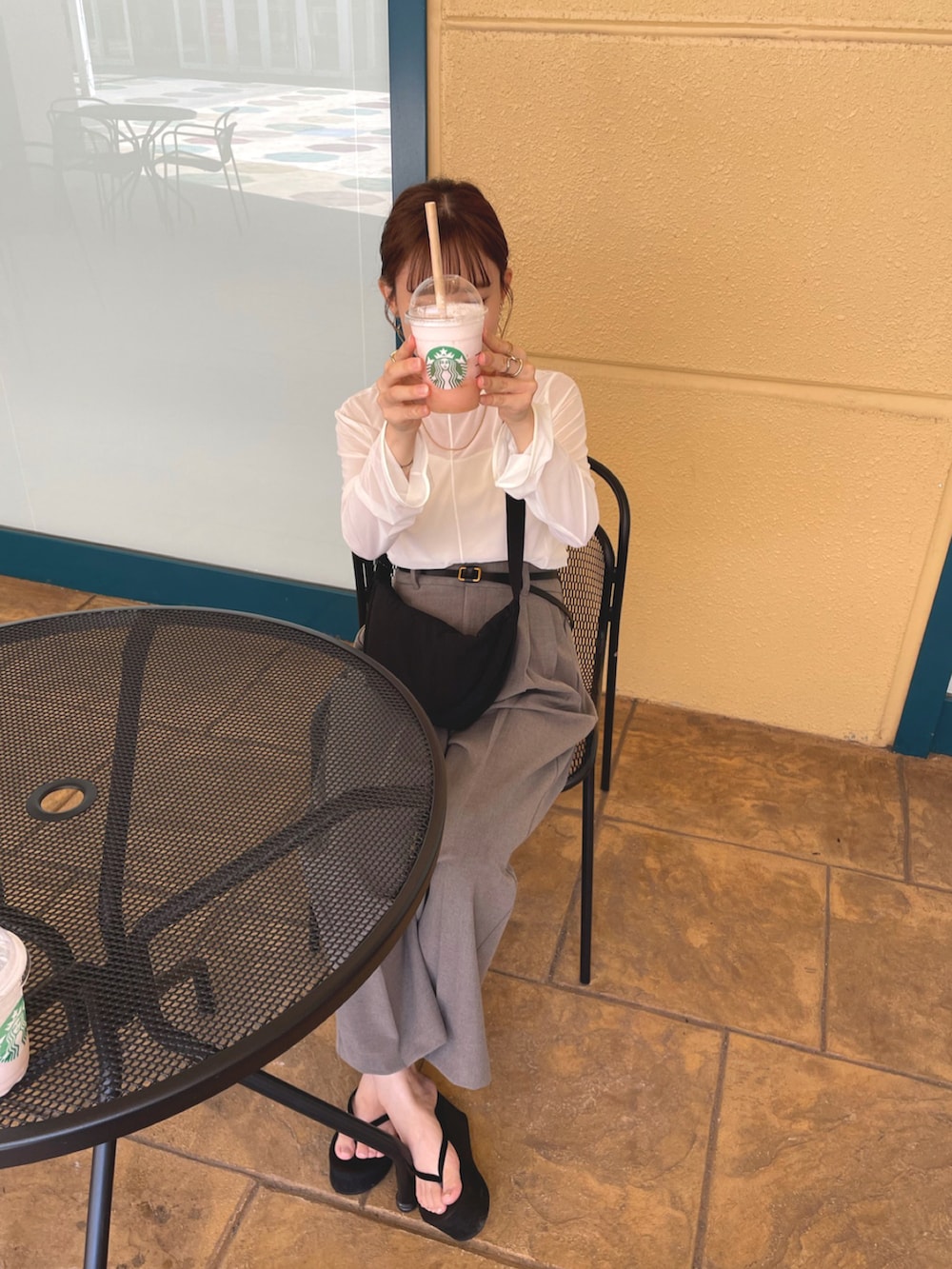 ホワイト系のトップス、ブラウン系のパンツ、ブラック系のショルダーバッグを着用したレディースの夏コーディネートの4枚目の写真