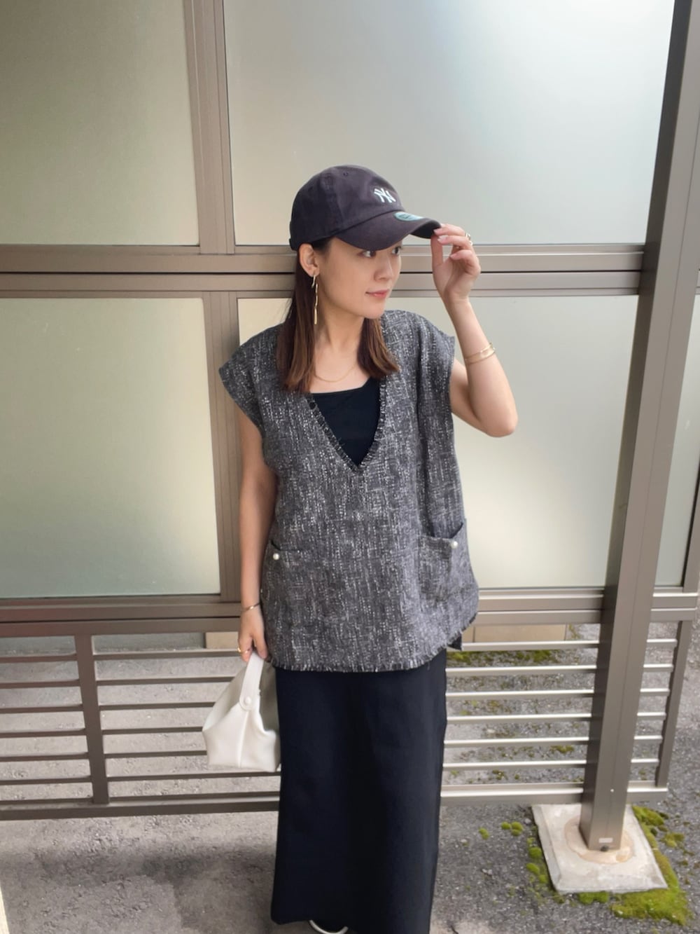 グレー系のベスト、ホワイト系のハンドバッグ、ブラック系のサンダルを着用したレディースの春コーディネートの2枚目の写真