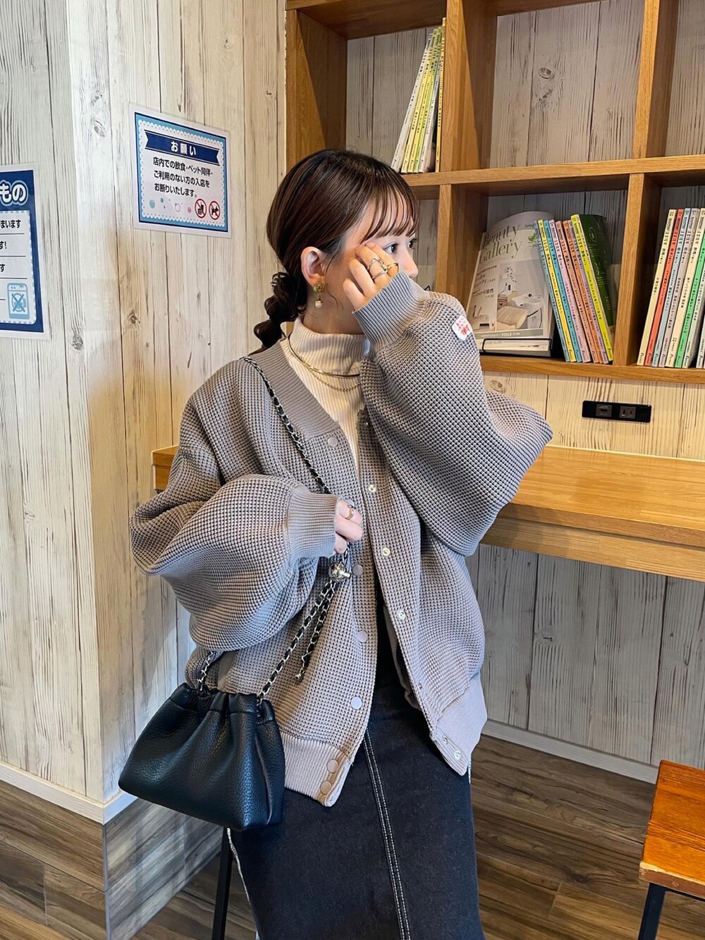 ブラウン系のカーディガン/ボレロ、ホワイト系のニット/セーター、ブラック系のデニムスカートを着用したレディースの冬コーディネートの3枚目の写真