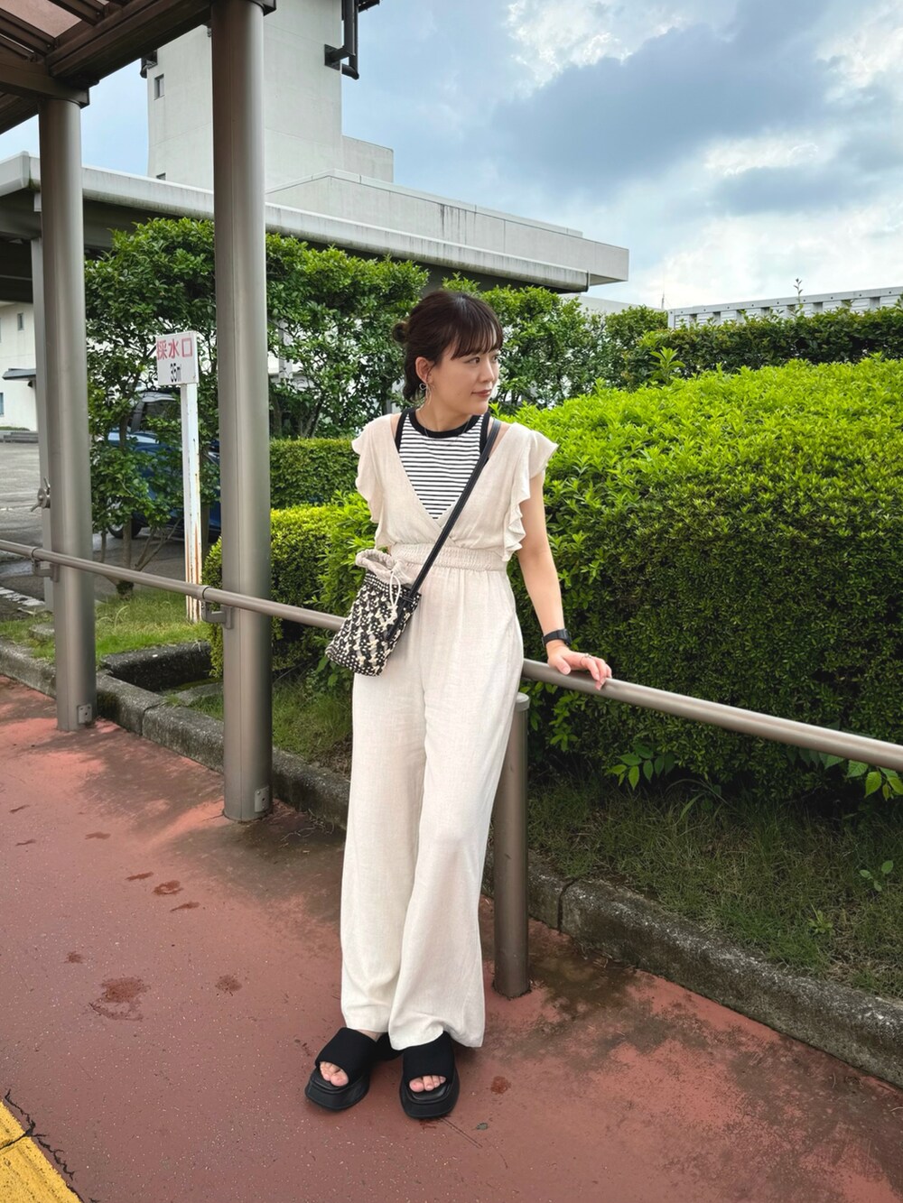 ホワイト系のオールインワン・サロペット、ブラック系のショルダーバッグ、ホワイト系のタンクトップを着用したレディースの夏コーディネートの5枚目の写真