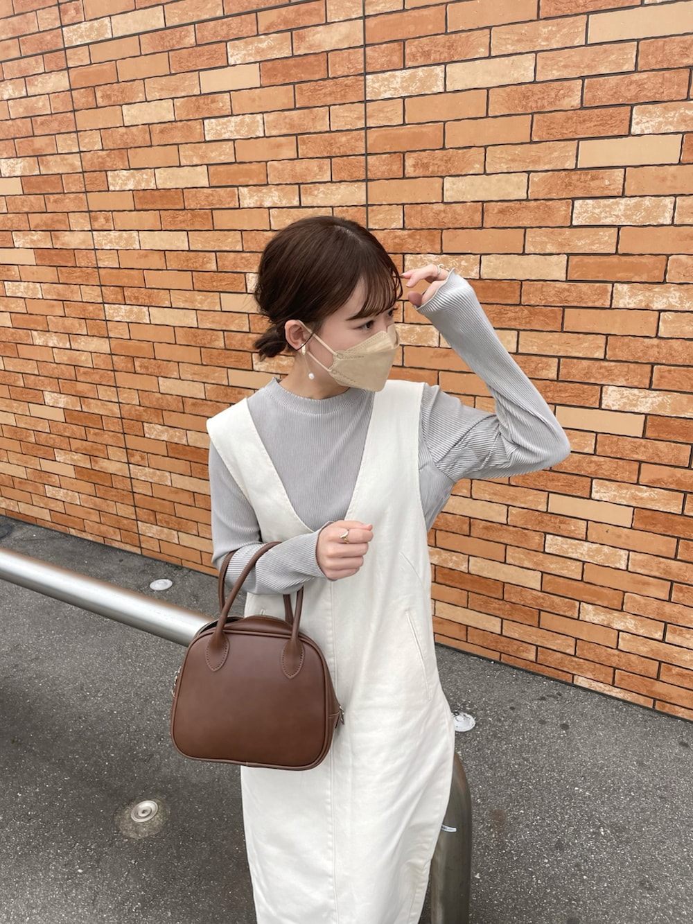 ベージュ系のTシャツ/カットソー、ホワイト系のジャンパースカート、ブラウン系のショルダーバッグを着用したレディースの春コーディネートの4枚目の写真