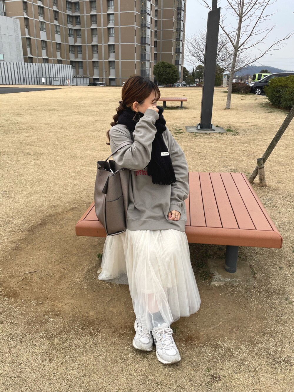 ベージュ系のスウェット、ホワイト系のスカート、ホワイト系のスニーカーを着用したレディースの冬コーディネートの2枚目の写真