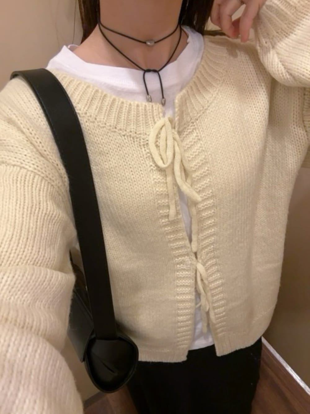 ホワイト系のカーディガン/ボレロ、ブラック系のスカート、ブラック系のショルダーバッグを着用したレディースの冬コーディネートの3枚目の写真