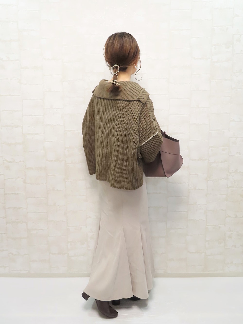 ブラウン系のニット/セーター、ベージュ系のスカート、ブラウン系のトートバッグを着用したレディースの冬コーディネートの2枚目の写真
