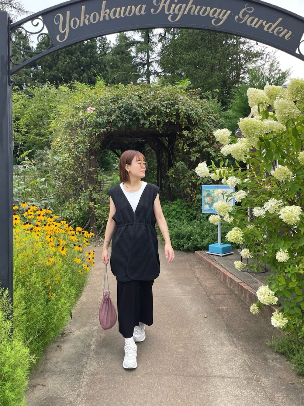 ブラック系のベスト、ホワイト系のタンクトップ、ピンク系のショルダーバッグを着用したレディースの夏コーディネートの5枚目の写真