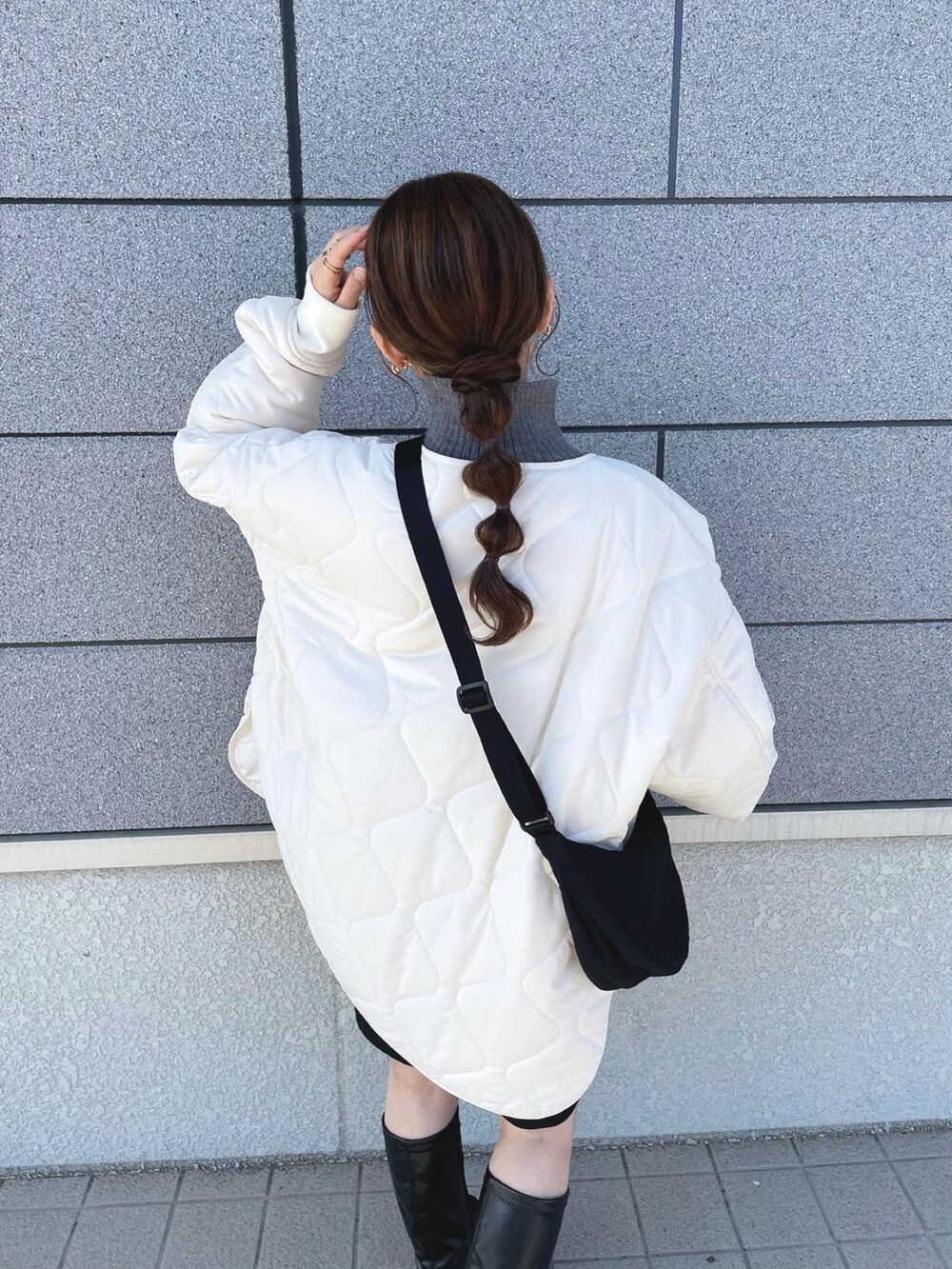 ホワイト系のブルゾン、グレー系のニット/セーター、ブラック系のショルダーバッグを着用したレディースの冬コーディネートの2枚目の写真