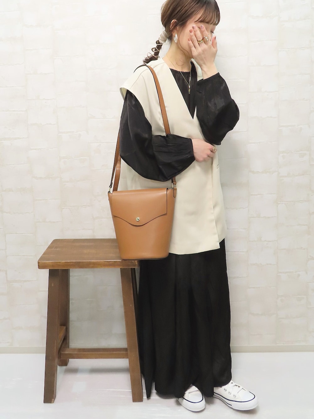 ブラック系のワンピース、ホワイト系のベスト、ホワイト系のスニーカーを着用したレディースの春コーディネートの3枚目の写真