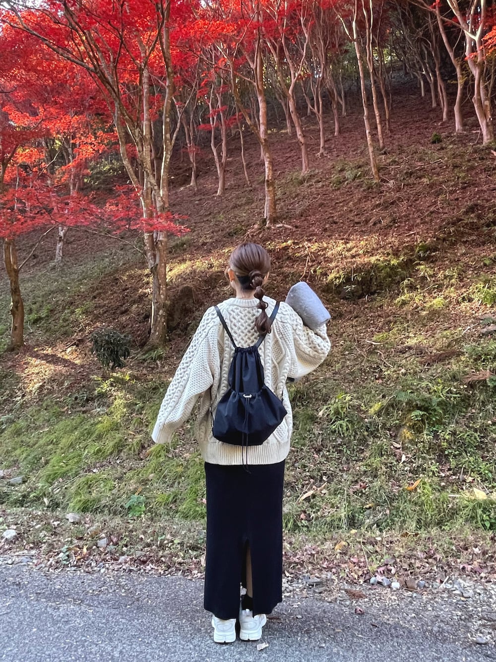 ホワイト系のニット/セーター、ブラック系のバックパック/リュック、グレー系のマフラーを着用したレディースの冬コーディネートの2枚目の写真