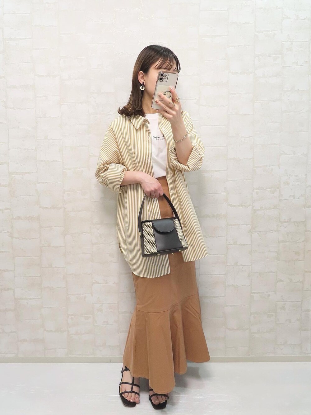 ブラック系のサンダル、イエロー系のシャツ/ブラウス、ホワイト系のTシャツ/カットソーを着用したレディースの春コーディネートの2枚目の写真