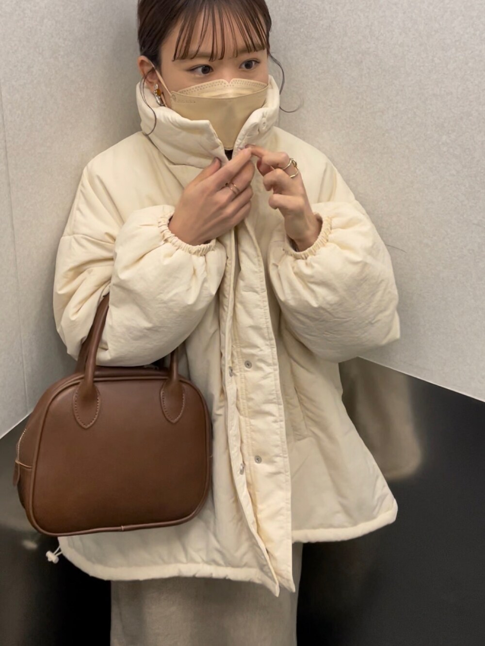 ホワイト系のブルゾン、ホワイト系のニット/セーター、ベージュ系のスカートを着用したレディースの冬コーディネートの5枚目の写真