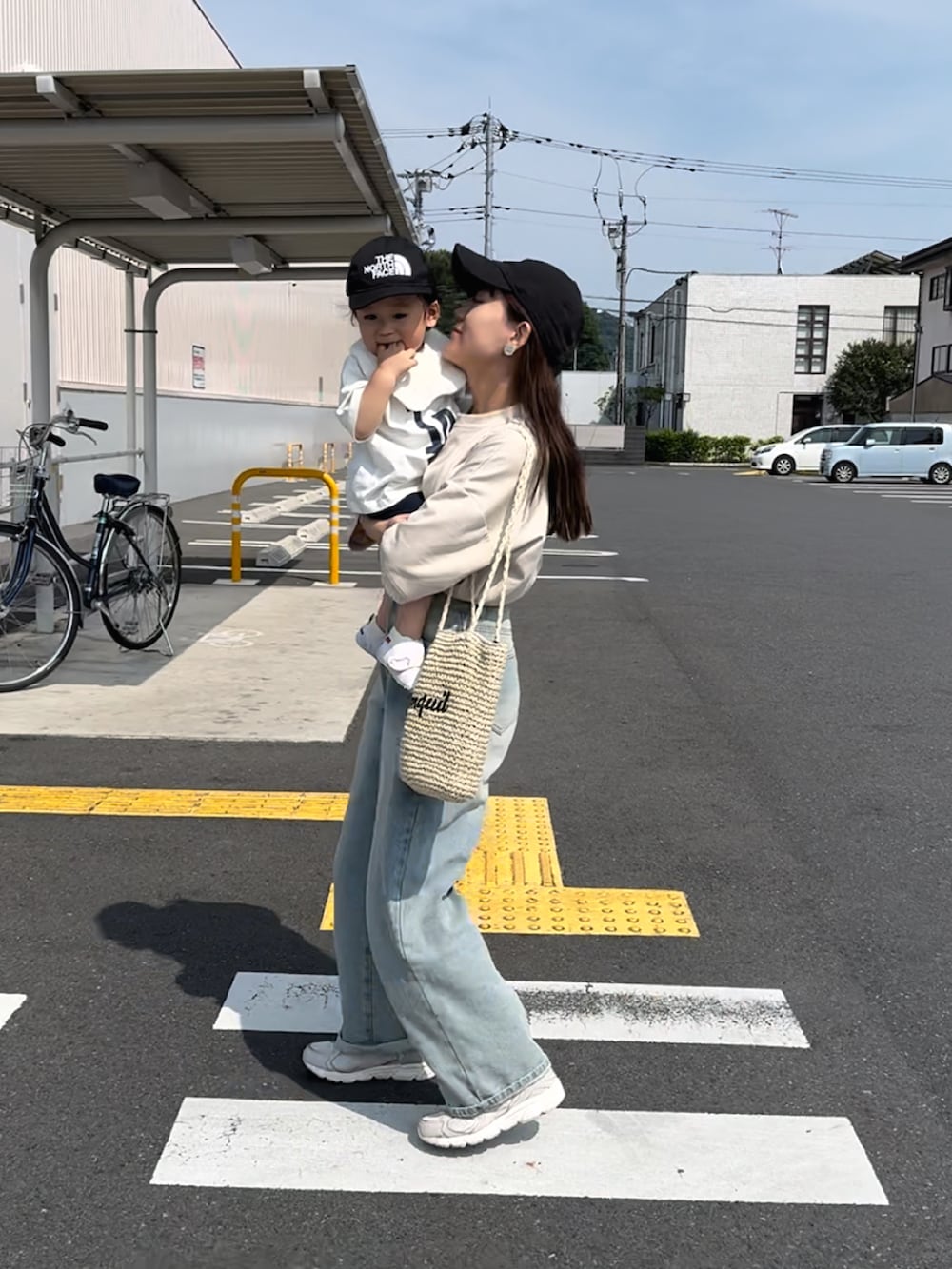 ベージュ系のトップス、ブルー系のデニムパンツ、ベージュ系のかごバッグを着用したレディースの夏コーディネートの2枚目の写真