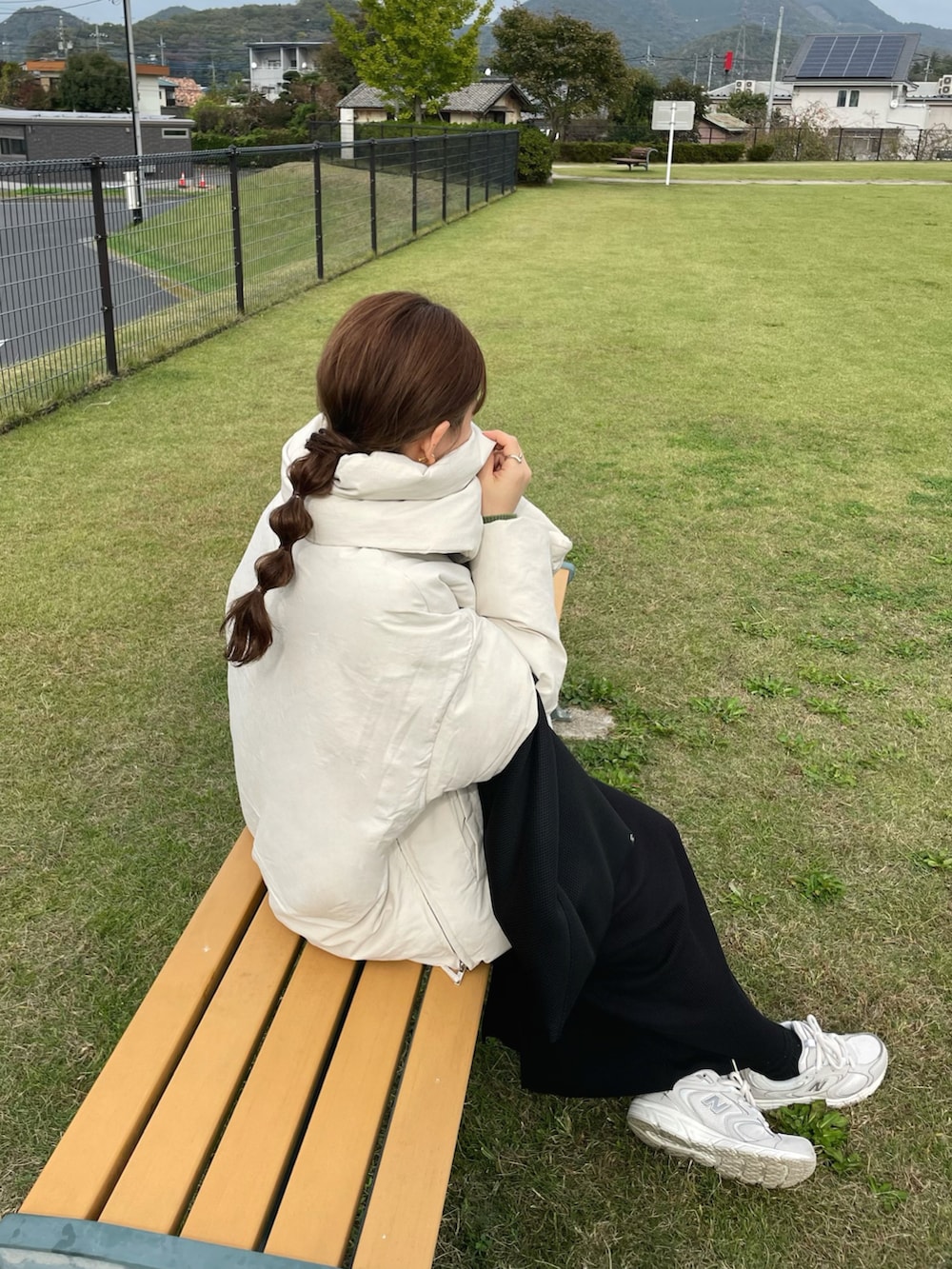 ブラック系のトートバッグ、ホワイト系のスニーカー、グリーン系のニット/セーターを着用したレディースの秋コーディネートの4枚目の写真