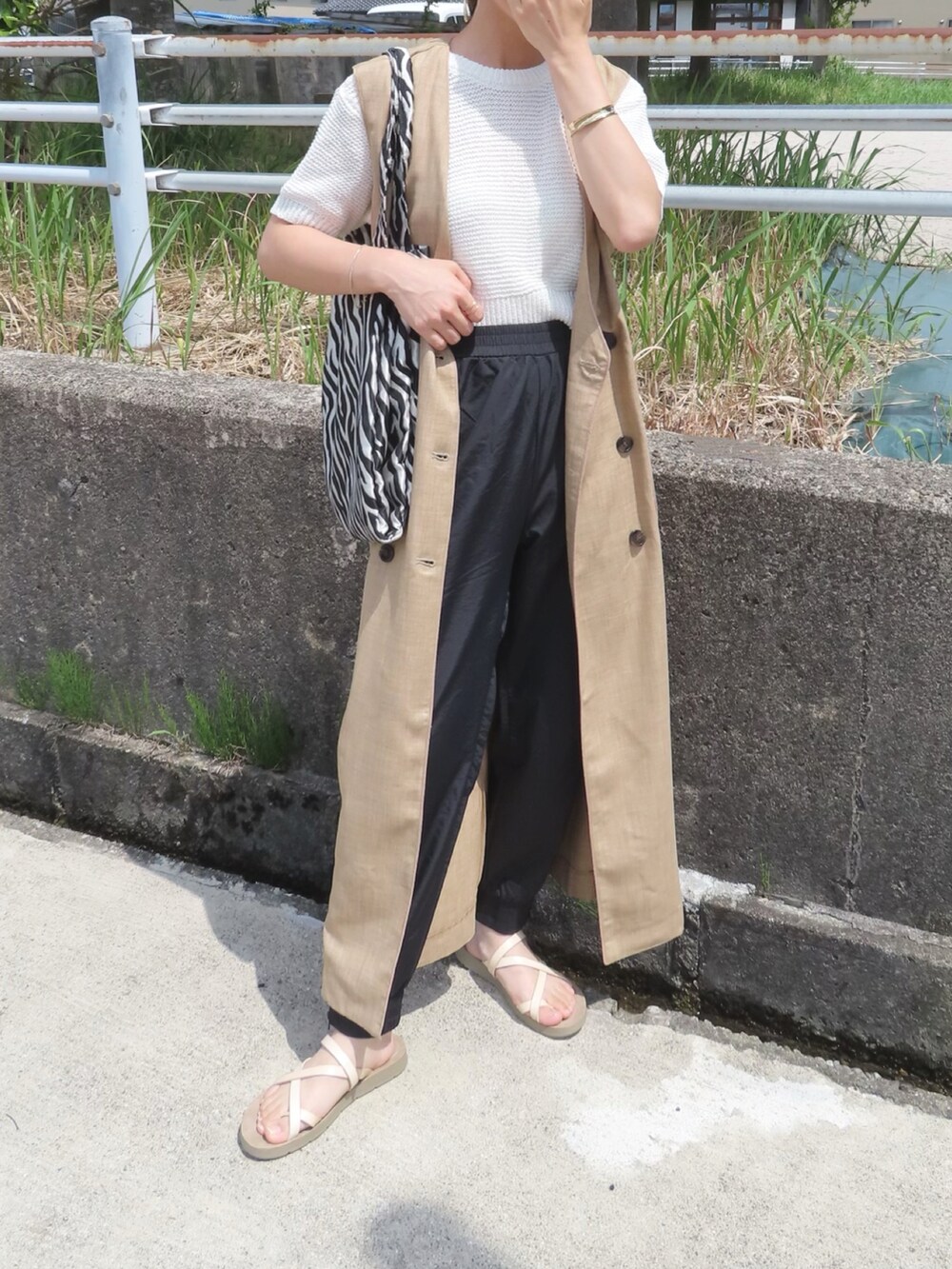 ベージュ系のベスト、ホワイト系のニット/セーター、ブラック系のその他パンツを着用したレディースの夏コーディネートの5枚目の写真