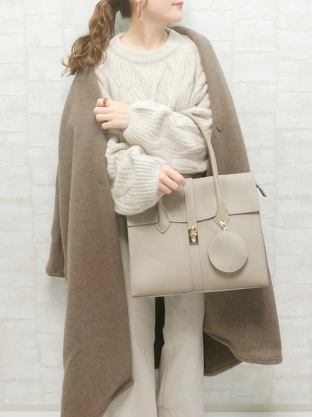 ブラウン系のその他アウター、ベージュ系のビジネスバッグ、ホワイト系のニット/セーターを着用したレディースの秋コーディネートの2枚目の写真