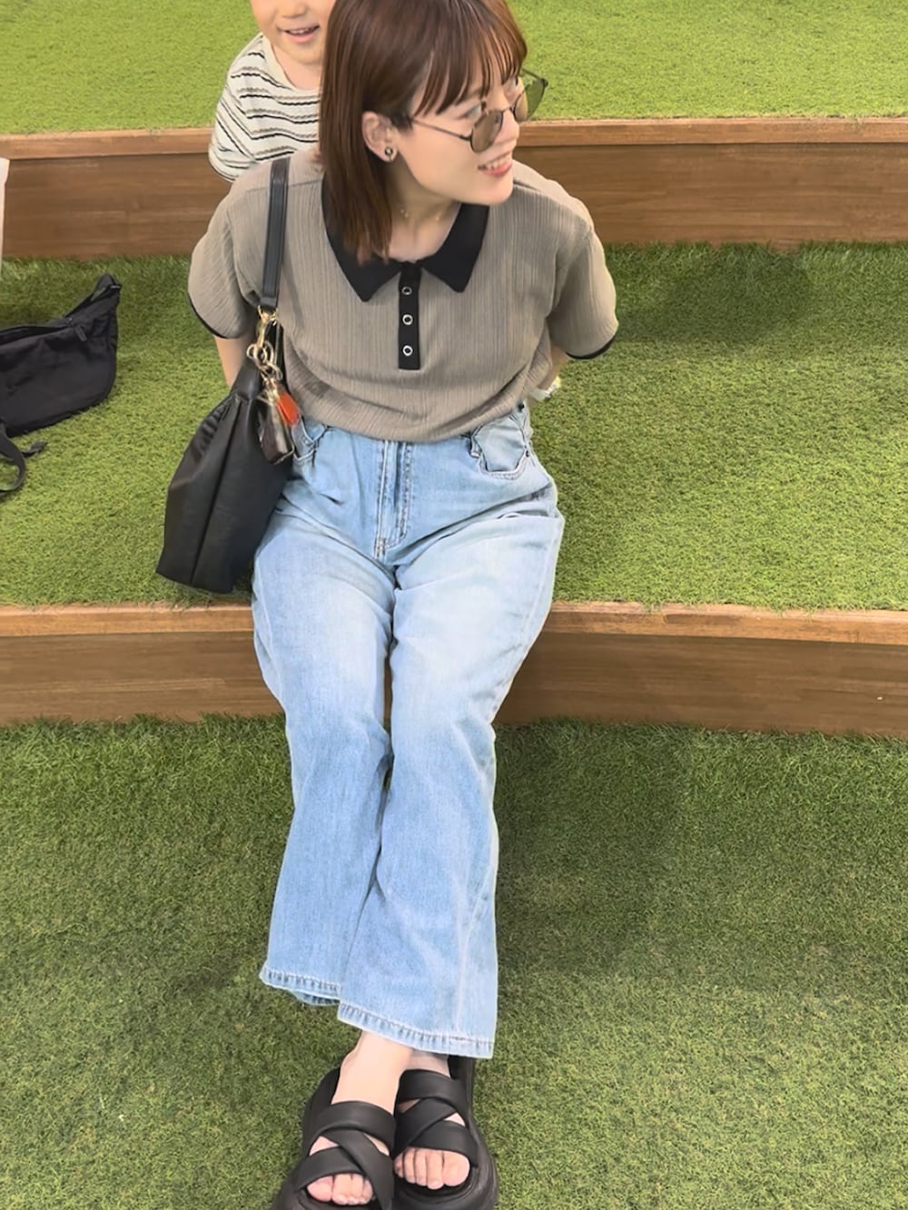 ベージュ系のTシャツ/カットソー、ブルー系のデニムパンツ、ブラック系のバッグを着用したレディースの秋コーディネートの2枚目の写真